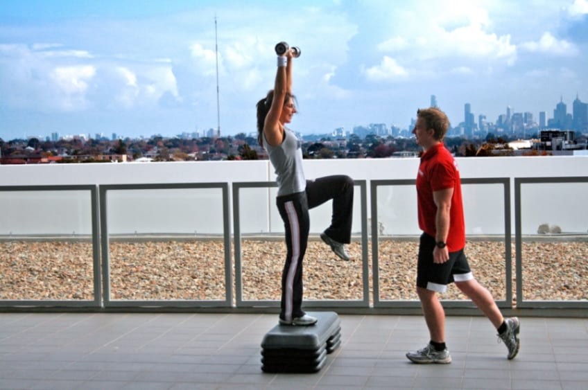 A Personal Trainer Helping A Woman Workout By The River In Melbourne